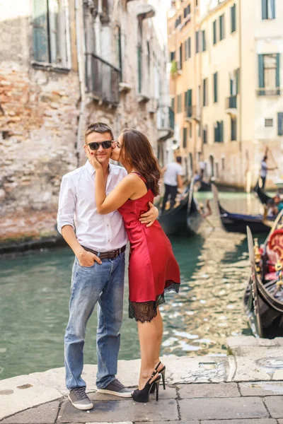 ヴェネツィアの運河の岸壁に彼のガール フレンドを受け入れる若い男 — ストック写真