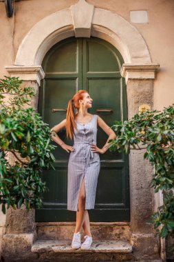 Eski yeşil kapının yanında poz çekici Kızıl saçlı kadın