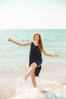 Siyah elbise su plajda çıplak ayakla poz içinde çekici Kızıl saçlı kadın