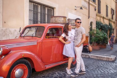 Genç çift kırmızı eski model araba Arnavut kaldırımlı sokakta yakınındaki poz
