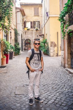 Boş Arnavut kaldırımlı sokakta yürüyen sırt çantası ile genç adam