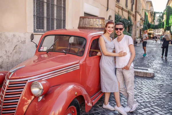 Giovane Coppia Posa Vicino Rosso Auto Epoca Strada Acciottolata — Foto Stock