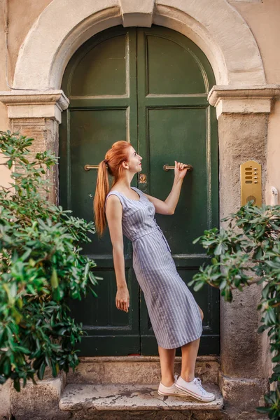 Eski yeşil kapının yanında poz çekici Kızıl saçlı kadın