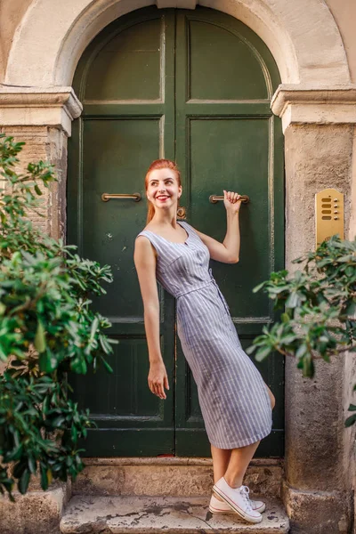 Eski yeşil kapının yanında poz çekici Kızıl saçlı kadın
