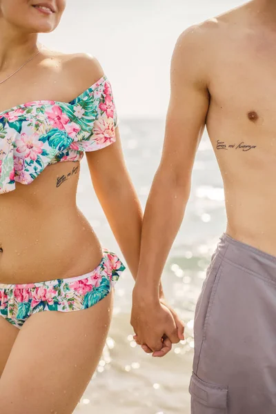 Young Couple Swimsuits Tattoo Inscriptions Holding Hands Beach — Stock Photo, Image