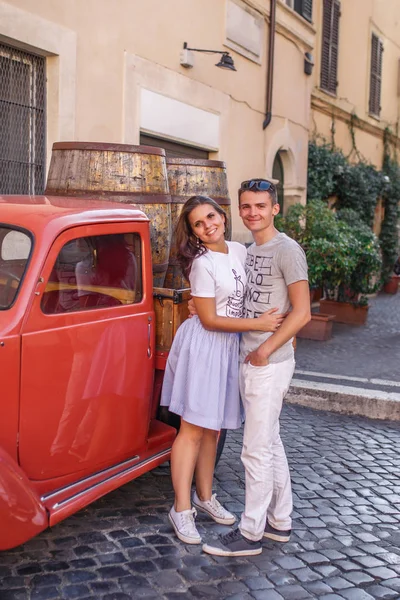 石畳の通り赤のビンテージ車に近いポーズ若いカップル — ストック写真