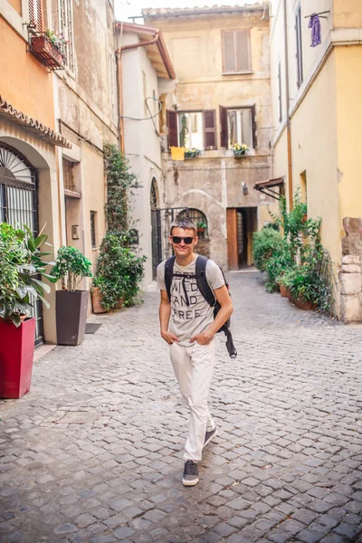 Boş Arnavut kaldırımlı sokakta yürüyen sırt çantası ile genç adam