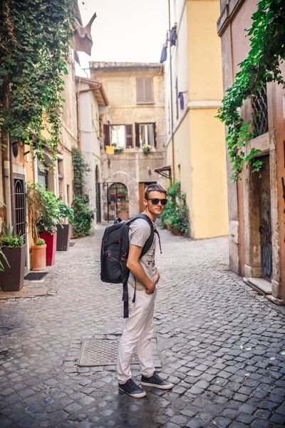 Young man with backpack walking on empty cobbled street