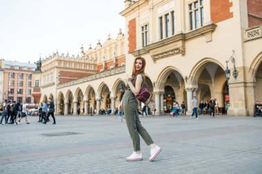 Mutlu traveler kız Ana Meydanı Krakow, Polonya üzerinde poz. Krakow Cloth Hall görünümüne