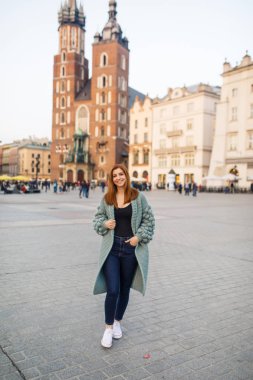 Mutlu traveler kız Ana Meydanı Krakow, Polonya üzerinde poz. Saint Mary Bazilikası görünümüne.