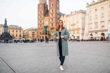 Mutlu traveler kız Ana Meydanı Krakow, Polonya üzerinde poz. Saint Mary Bazilikası görünümüne.
