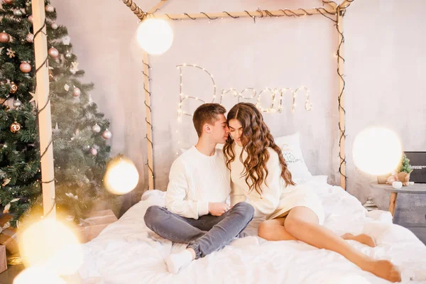 Jovem Casal Bonito Estão Sentados Cama Fundo Árvore Natal Sorrindo — Fotografia de Stock