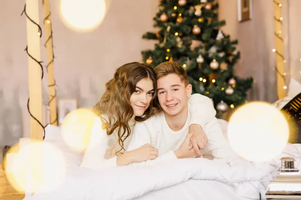 Jovem Casal Bonito Estão Sentados Cama Fundo Árvore Natal Sorrindo — Fotografia de Stock