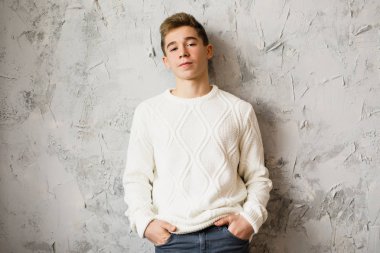 gri bir arka plan üzerinde beyaz bir ceket genç yakışıklı çocuk duruyor