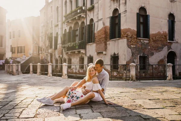 Young beautiful couple girl in dress man in white shirt walk through the streets of Venice Italy