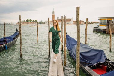 Yeşil giysili Kızıl saçlı Genç güzel kız güzel Venedik bakan su kenarında duruyor