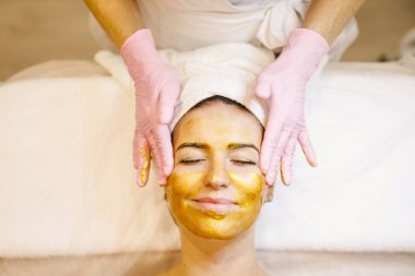 Kadın spa salonunda yüz masajı yaptırıyor.