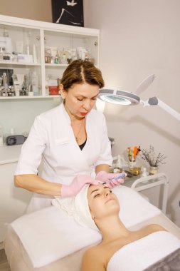 Güzellik uzmanı güzellik salonunda yüz maskesi yapıyor.
