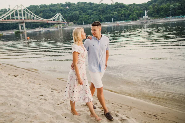 お互いを抱いて川を歩く若いカップル — ストック写真