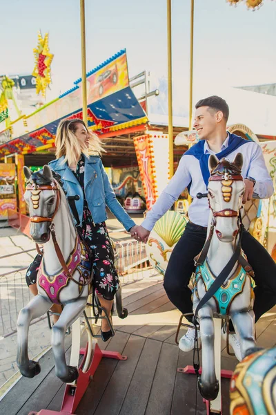 Młoda Para Siedzi Konie Carousel Trzymając Ręce — Zdjęcie stockowe