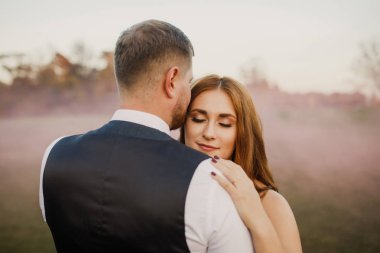 Güzel bir çift gün batımında sarılıp gülümsüyor.