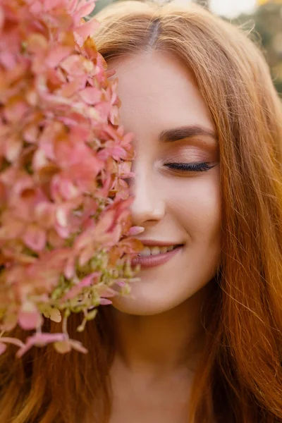 Elinde çiçek çelengi olan güzel bir genç kadının portresi.