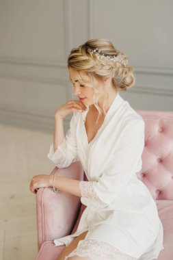 genç güzel düğün gelin pembe bir yatakta parlak bir odada oturuyor ve gülümseyen