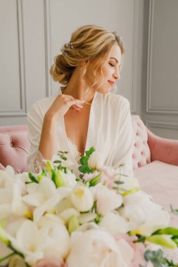 genç güzel düğün gelin pembe bir yatakta parlak bir odada oturuyor ve gülümseyen