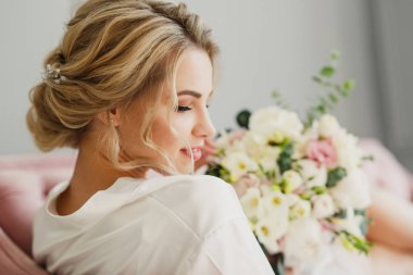 genç güzel düğün gelin pembe bir yatakta parlak bir odada oturuyor ve gülümseyen