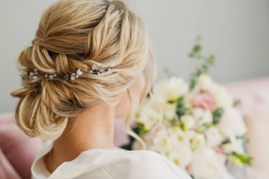 genç güzel düğün gelin pembe bir yatakta parlak bir odada oturuyor ve gülümseyen