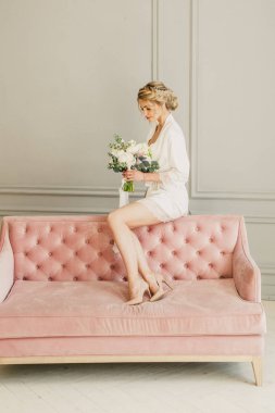 genç güzel düğün gelin pembe bir yatakta parlak bir odada oturuyor ve gülümseyen