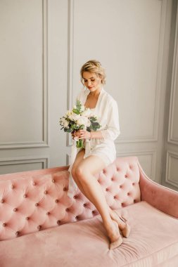 genç güzel düğün gelin pembe bir yatakta parlak bir odada oturuyor ve gülümseyen