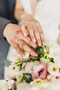 çiçekler üzerinde düğün yüzükleri ile gelin ve damat eller