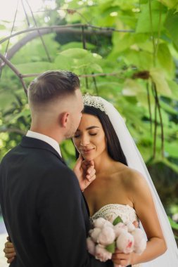 genç güzel düğün çift gelin ve damat parkta günbatımında ayaktadır ve gülümseyen güzel elbise damat gelini şık giyinmiş