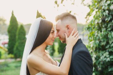 genç güzel düğün çift gelin ve damat parkta günbatımında ayaktadır ve gülümseyen güzel elbise damat gelini şık giyinmiş