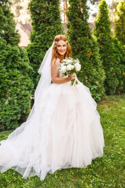 Parkta poz veren beyaz gelinlikli güzel gelin