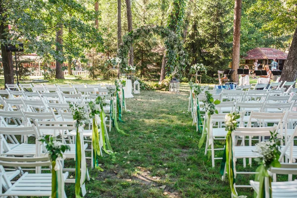 Σειρές Από Διακοσμημένα Καρέκλες Και Floral Αψίδα Στην Υπαίθρια Σκηνή — Φωτογραφία Αρχείου