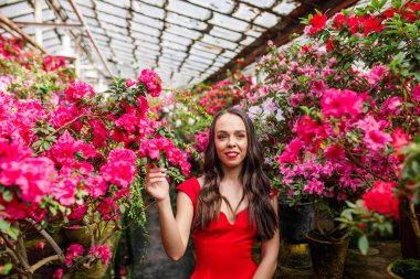 Çiçeklerle güzel bir botanik bahçede kırmızı bir elbise genç güzel esmer Portresi