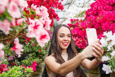 Çiçeklerle güzel bir botanik bahçede kırmızı bir elbise genç güzel esmer Portresi