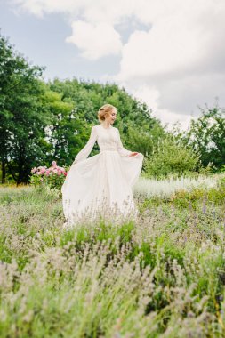 Beyaz elbiseli güzel gelin çimlerin üzerinde duruyor.
