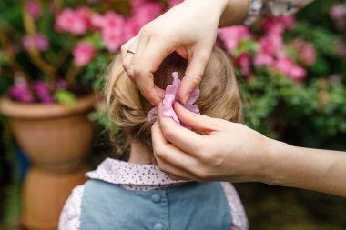 Kadın elinde çocuk saçında küçük bir çiçek tutuyor.