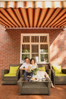 Çekici genç gelin ve damat kahve içip arka planda kafede oturuyorlar.