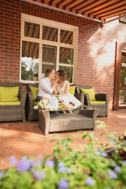 Çekici genç gelin ve damat kahve içip arka planda kafede oturuyorlar.