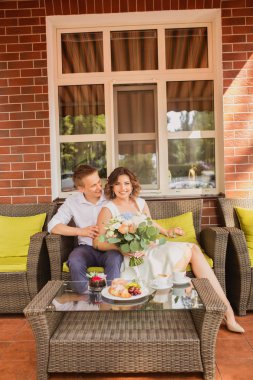 Çekici genç gelin ve damat kahve içip arka planda kafede oturuyorlar.