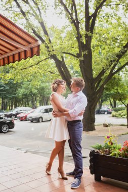 Çekici genç gelin ve damat arka planda kafenin yanında yürüyorlar.
