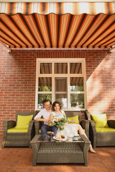 Çekici genç gelin ve damat kahve içip arka planda kafede oturuyorlar.