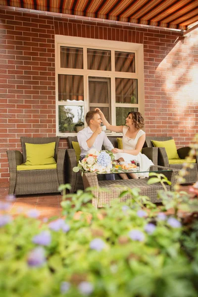 Çekici genç gelin ve damat kahve içip arka planda kafede oturuyorlar.