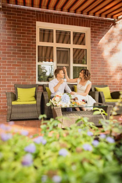 Çekici genç gelin ve damat kahve içip arka planda kafede oturuyorlar.