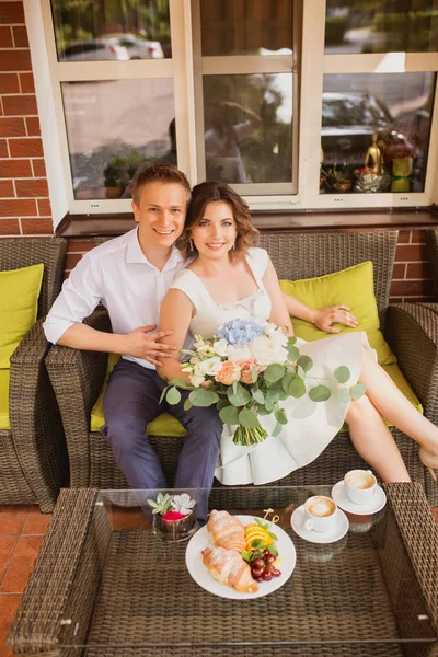 魅力的な若い花嫁と新郎がコーヒーを飲みながら屋外のカフェに座って — ストック写真