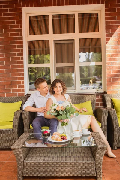 Çekici genç gelin ve damat kahve içip arka planda kafede oturuyorlar.